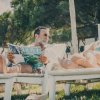 Due persone rilassate su lettini all'aperto; una legge una rivista.