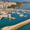 Vista aerea di un porto con barche e una città sullo sfondo.
