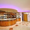 Bar con bancone curvo e illuminazione soffusa viola.