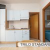 Cucina compatta con pensili azzurri, tavolo e porte interne aperte.