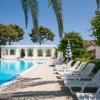 Piscina lunga con sdraio allineate e palme sullo sfondo.