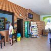 Interno di un bar con mobili moderni, un uomo al bancone e scaffali con snack.