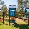 Un'area giochi per bambini con strutture in legno e plastica su un prato verde.