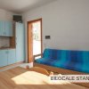 Cucina e salotto con mobili azzurri, divano blu e porta di legno.