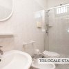Bagno con lavabo, specchio rotondo, doccia e bidet.