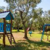 Un parco giochi con strutture di legno e scivoli. Alberi sullo sfondo.