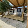 Veranda in legno con copertura e sedie, davanti a una casa mobile.