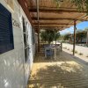 Veranda con tavolo e sedie, sotto copertura di canne e accanto a una casa mobile.