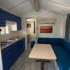 Cucina e salotto con divano blu e tavolo in legno chiaro.
