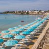 Ombrelloni azzurri allineati lungo una spiaggia sabbiosa.