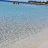 Acqua cristallina in spiaggia sabbiosa.