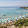 Spiaggia con ombrelloni turchesi e mare calmo.