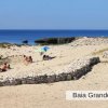 Spiaggia sabbiosa con ombrelloni e persone vicine al mare.