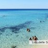 Mare azzurro, persone nuotano vicino a riva.